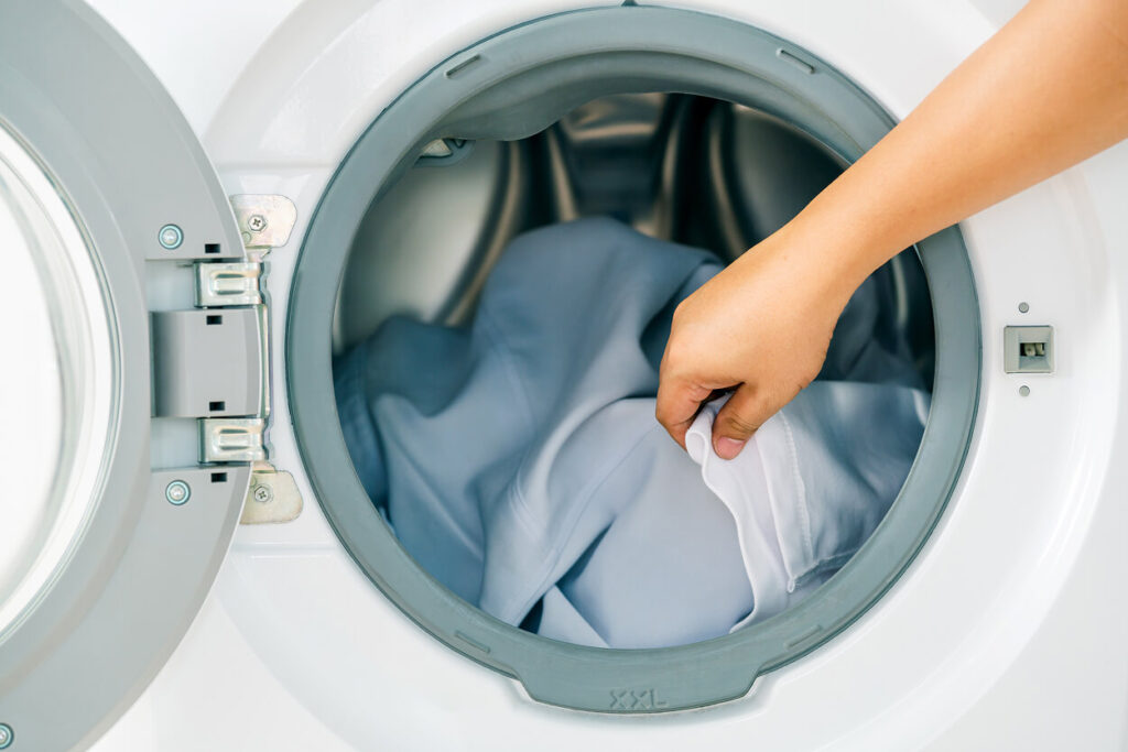 Funcionário a colocar roupa na máquina de lavar da lavandaria em Portimão